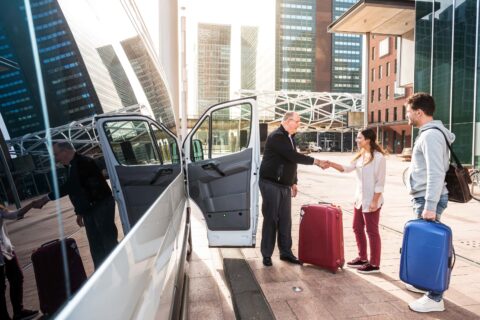 Driver,of,a,airport,shuttle,minivan,,greeting,his,passengers,with